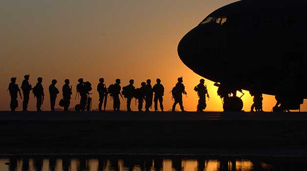 silhouette of military personnel boarding aircraft